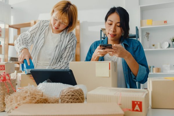 Young Asia businesswomen using mobile phone call receiving purch Young Asia businesswomen using mobile phone call receiving purchase order and check product on stock work at home office. Small business owner, online market delivery, lifestyle freelance concept.