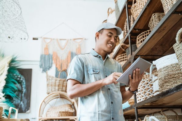 young-entrepreneur-smiles-while-holding-digital-tablet-while-standing-craft-shop young-entrepreneur-smiles-while-holding-digital-tablet-while-standing-craft-shop